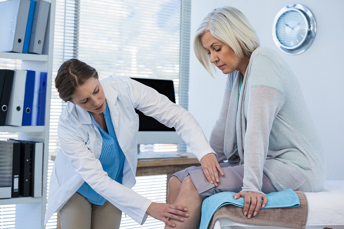 Doctor examining an older woman's knee in a clinic Doctor examining an older woman's knee in a clinic