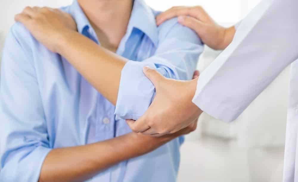 Clinician supporting a patient's arm and shoulder during a physical therapy session Clinician supporting a patient's arm and shoulder during a physical therapy session