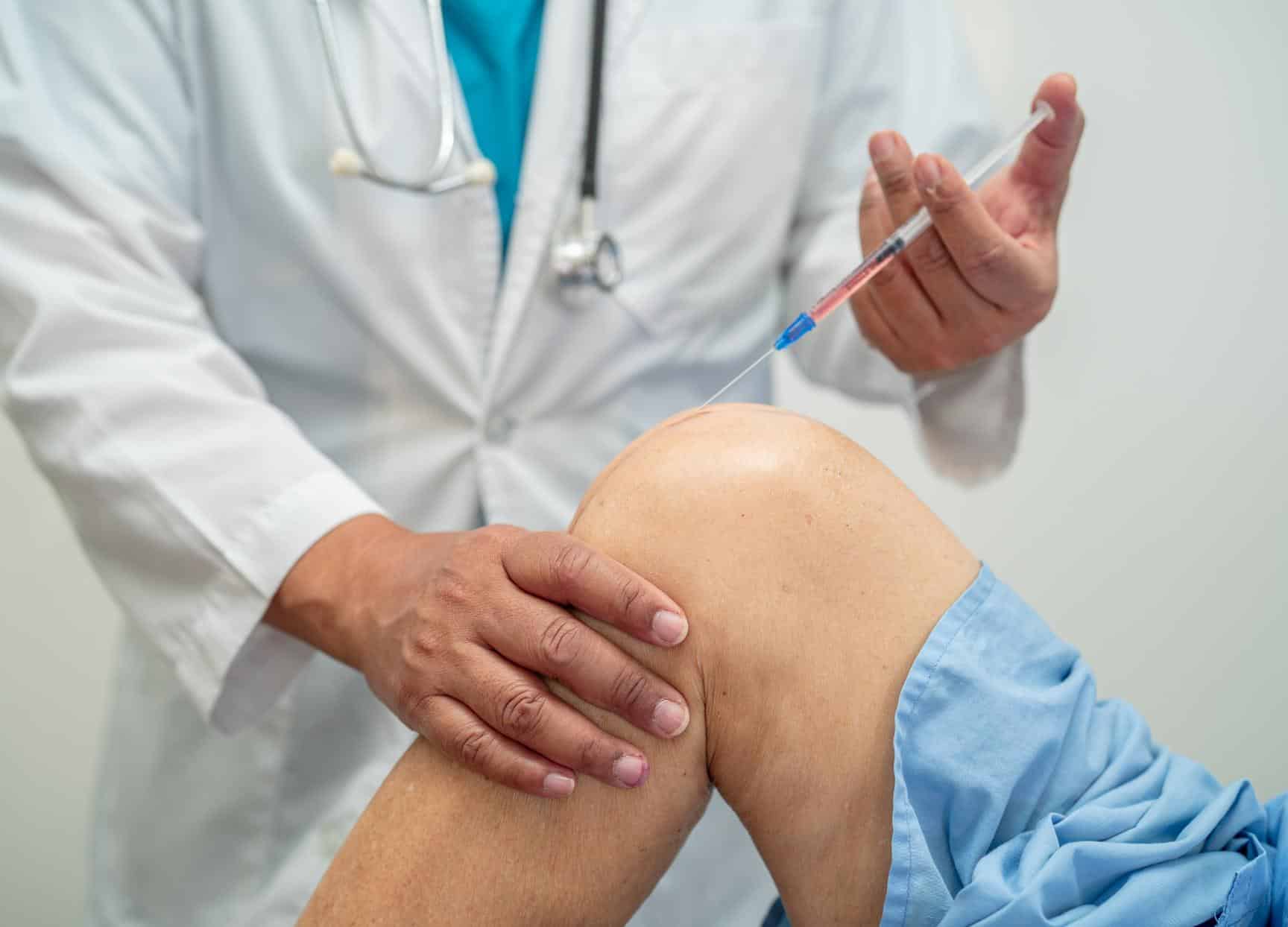 Doctor giving an injection into a patient's knee Doctor giving an injection into a patient's knee