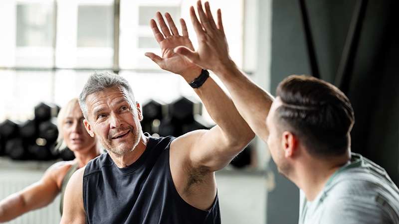 Two mature male athletes celebrating with high five during cross training workout